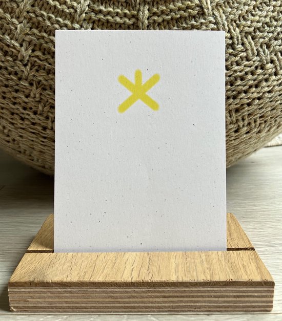 Een witte kaart met een gele ster in het midden, in een houten display.