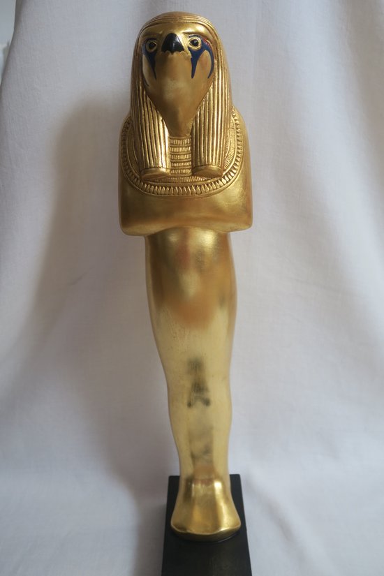 Gouden beeldje van Horus, rechtopstaand op een zwarte sokkel, met gedetailleerd hoofd en vleugels.