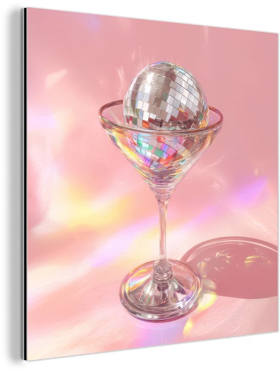 Boule à facettes dans un verre à martini avec des reflets de lumière pastel sur fond rose.