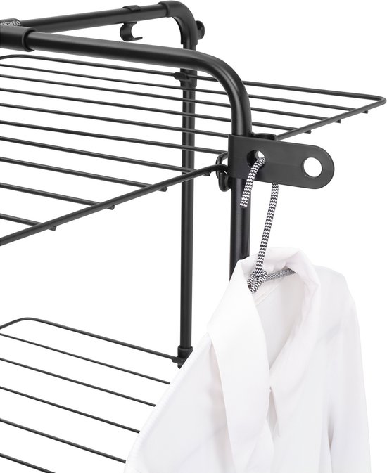 Zwarte metalen droogtoren met een wit overhemd dat aan een gespikkelde draad hangt.