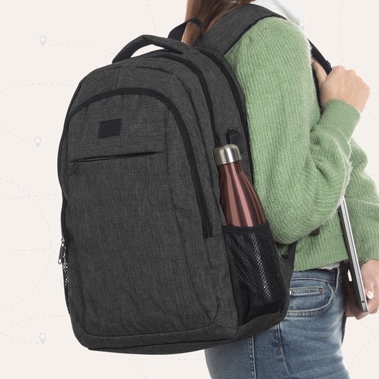 Vrouw met groene trui draagt donkergrijze rugzak met roze waterfles in het zijvak. Ze houdt een laptop vast.