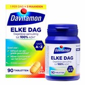 Davitamon Elke Dag doos en potje met 90 tabletten. De verpakking is blauw met gele, oranje, rode en groene accenten. Één tablet is zichtbaar.