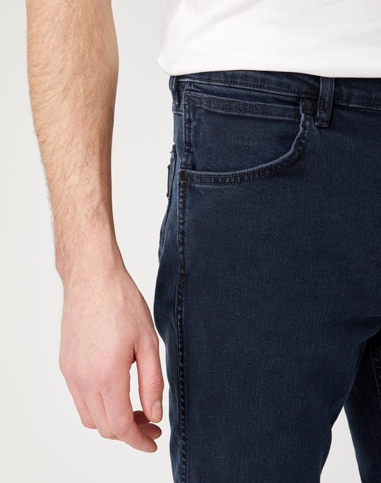 Close-up van de zijkant van een donkerblauwe Wrangler-spijkerbroek.