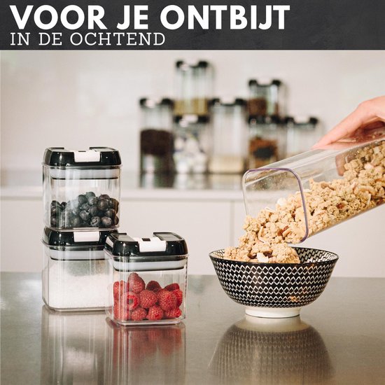 Doorzichtige voorraadpotten met zwarte deksels, gevuld met bosbessen, suiker en frambozen, terwijl muesli in een kom wordt gegoten.