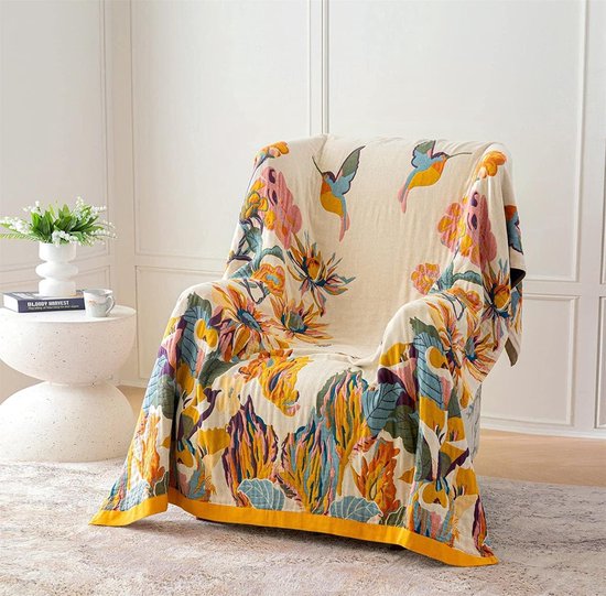 Dubbelzijdige deken met bloemen- en vogeltjesprint, gedrapeerd over een fauteuil.