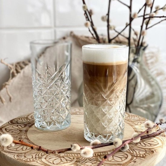 Deux verres hauts gravés avec un motif en losange. Un verre est rempli d'une boisson au café en couches.