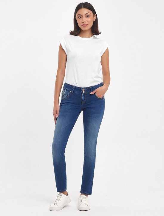 Model in een donkerblauwe spijkerbroek met een witte top. De broek heeft een lichte wassing en twee knopen bij de taille.