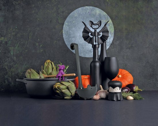 Zwarte soeplepel in de vorm van een katje met pootjes, in een Halloween-setting met pompoenen en groenten.
