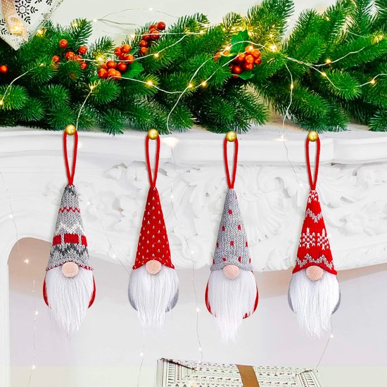 Quatre nains de Noël avec des bonnets tricotés rouges, gris et blancs avec des motifs, suspendus au-dessus d'une cheminée.