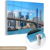 MuchoWow® Glasschilderij 120x80 cm - Schilderij acrylglas - Brooklyn Bridge in Amerika onder een blauwe hemel - Foto op glas - Schilderijen