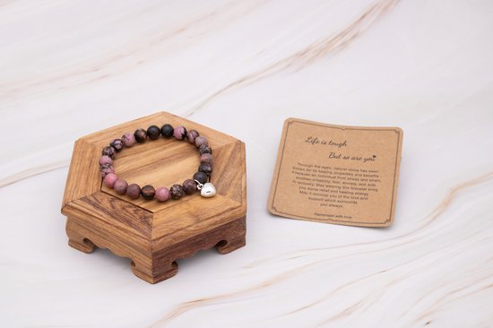 Roze en bruine kralenarmband met hartvormige hanger, naast een kaart.