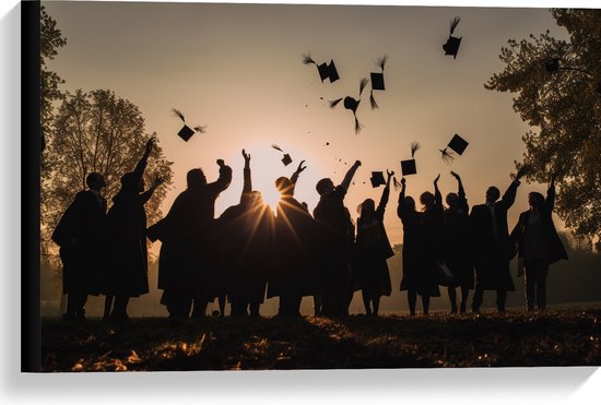Een groep studenten in toga's gooit hun afstudeerpetten in de lucht bij zonsondergang.