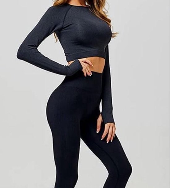 Model in een zwarte, nauwsluitende sportoutfit: een crop top met lange mouwen en een legging met hoge taille.