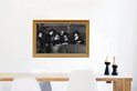 Een groep mannen in klederdracht met hoeden staat rond een tafel, ingelijst in een gouden lijst.