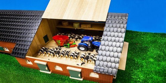 Gedetailleerde speelgoedboerderij met rood baksteen, zwart dak en groene deuren.