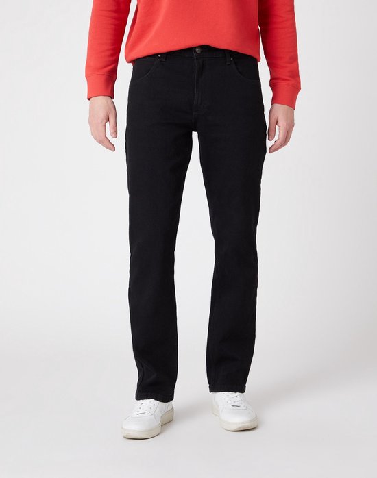 Man in een zwarte jeans en witte sneakers, met een rode trui.