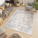 Un tapis gris clair à motif vintage, dans un salon avec un canapé gris, un fauteuil et des meubles en bois.