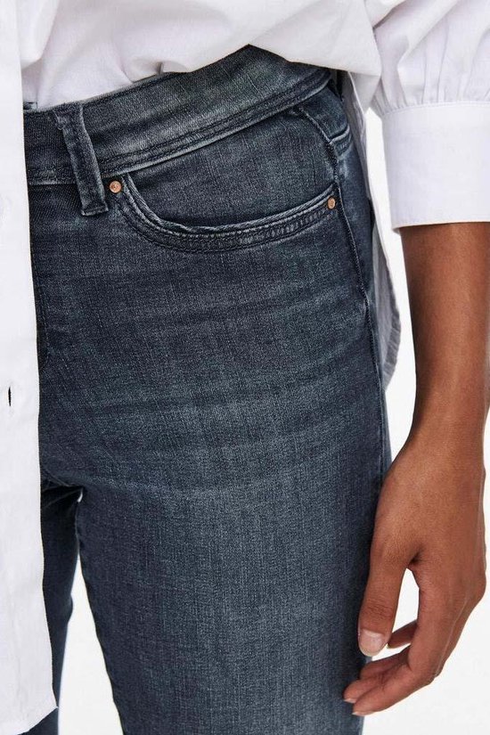 Detailopname van de tailleband en zakken van een blauwe skinny spijkerbroek.