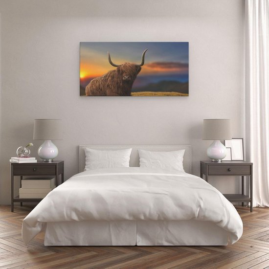 Impression sur toile d'une vache écossaise highland sur une colline, accrochée au-dessus d'un lit dans une chambre.
