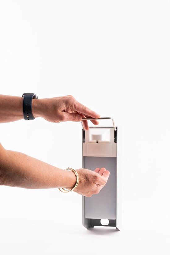 Vrouw gebruikt elleboogdispenser. Metalen houder met witte pomp. De dispenser hangt aan de muur.