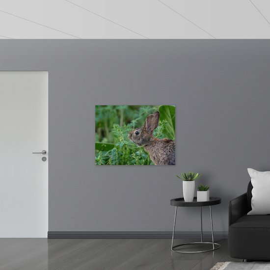 WallClassics - Poster Glanzend – Bruin Konijn Ruikt aan Groene Plant - 100x75 cm Foto op Posterpapier met Glanzende Afwerking