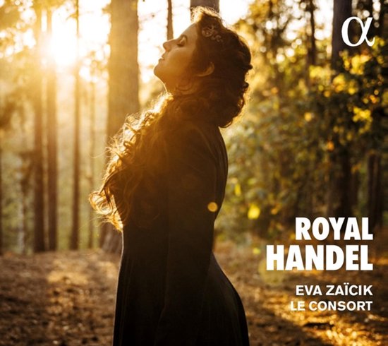 Vrouw met krullend haar, gekleed in een donkere jurk, staat in een bos. "ROYAL HANDEL EVA ZAÍCIK LE CONSORT"