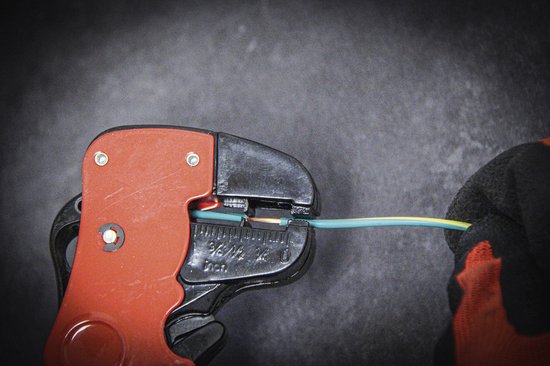 Rood-zwarte striptang die een groen-gele kabel stript.