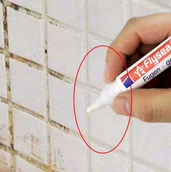 Hand gebruikt Flysea voegstift wit met dop, op witte tegels met grijze voegen.