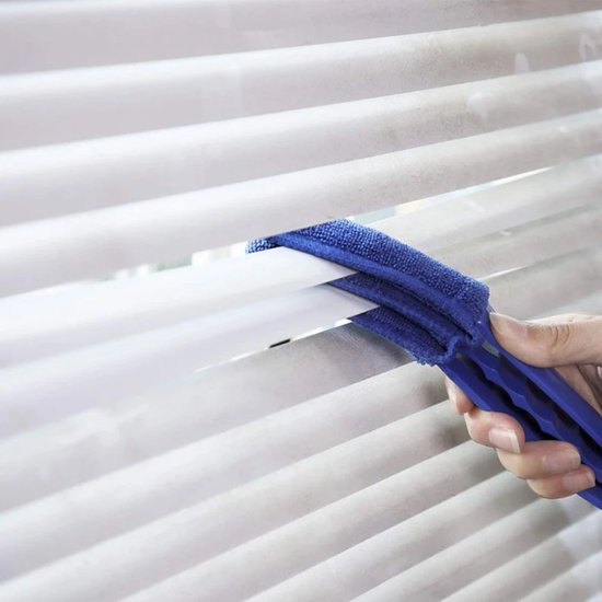 Hand met blauwe lamellenreiniger die witte lamellen schoonmaakt.