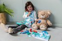 Een jong meisje met een dokterspruim en stethoscoop speelt met een teddybeer.