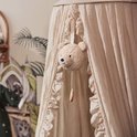 Lichtbruine teddybeer-muziekhanger hangend in een hemelbed.