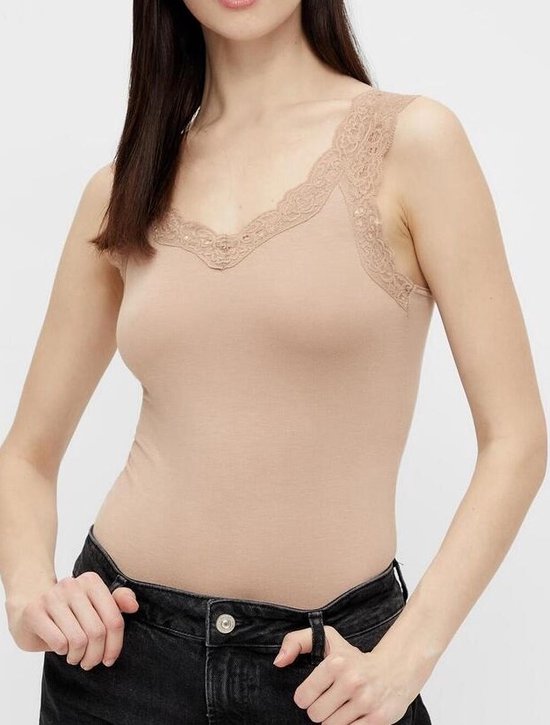 Model in beige hemd met kanten rand, gedragen met zwarte jeans.