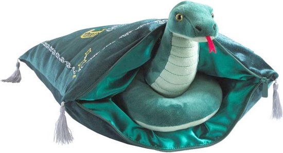 Serpent en peluche vert avec la langue sortie, posé sur une housse de coussin vert foncé ornée d'étoiles dorées et de glands.