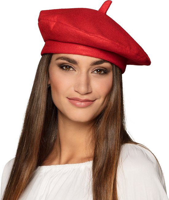 Een vrouw met lang bruin haar draagt een felrode baret boven een witte top.