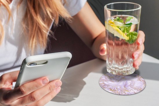 Sous-verre rond à motif marbre lilas et or, à côté d'un verre d'eau et d'un téléphone.