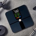 Zwarte Robi S9 weegschaal op een grijze ondergrond, met dumbbells op de achtergrond.