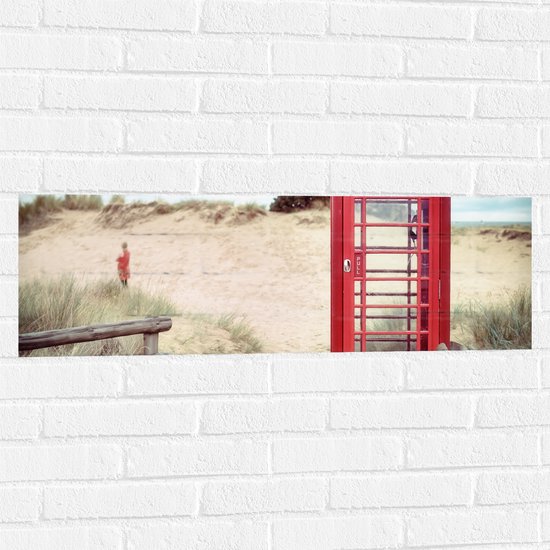 WallClassics - Muursticker - Rode Telefooncel in Duinen - 90x30 cm Foto op Muursticker