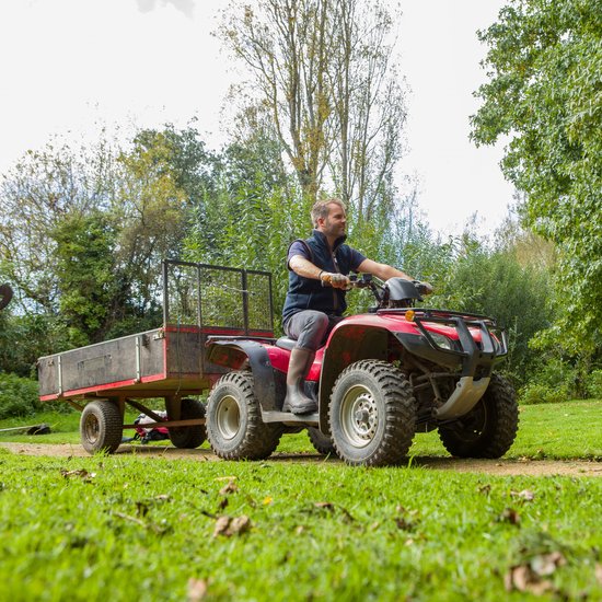 Man op rode quad met aanhanger, draagt bruine Muck Boot Derwent II laarzen.