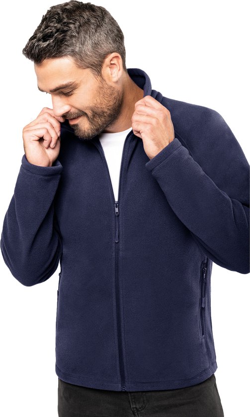 Man met donkerblauwe fleece jas van Kariban, rits gesloten, witte t-shirt eronder.