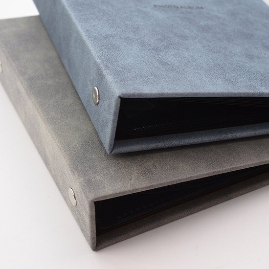 Twee fotoalbums op elkaar, een lichtblauwe en een grijze, beide met metalen ringen. Blauwe album is bovenop.