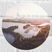 WallClassics - Muursticker Cirkel - Bovenaanzicht van Begroeide Stad aan het Water - 20x20 cm Foto op Muursticker