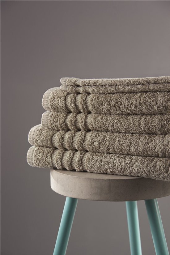 Pile de serviettes taupe avec détail côtelé sur un tabouret en béton.