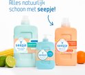 Drie Seepje flessen: pastelgroene universele wasmiddel, lichtblauwe handzeep, en oranje vlekverwijderaar, met maïs, limoen en sinaasappel.