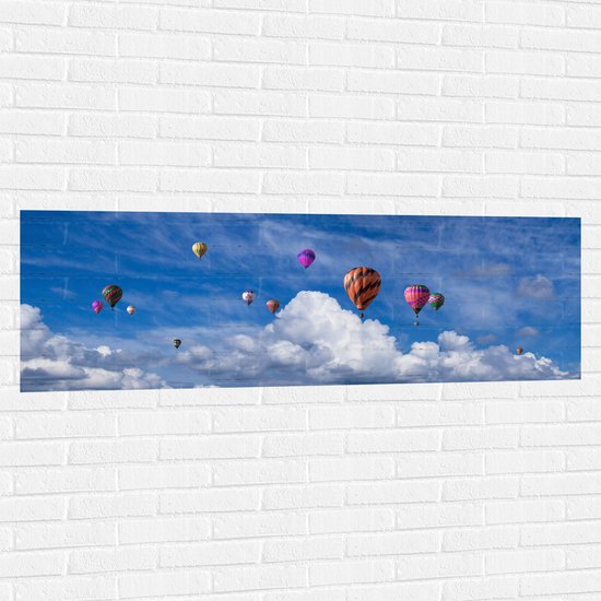 WallClassics - Muursticker - Groepje Gekleurde Luchtballonnen bij Wolken in Blauwe Lucht - 150x50 cm Foto op Muursticker