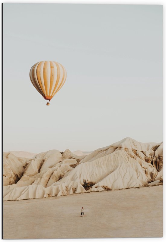 Dibond - Oranje met Wit Gestreepte Luchtballon Vliegend boven Beige Rotsen - 70x105 cm Foto op Aluminium (Met Ophangsysteem)