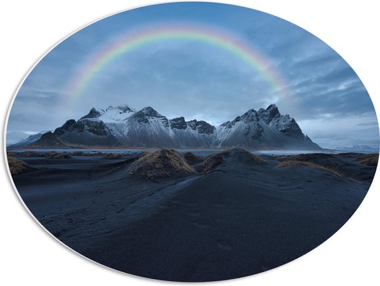 PVC Schuimplaat Ovaal - Regenboog boven Berggebied - 56x42 cm Foto op Ovaal (Met Ophangsysteem)