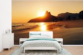 Behang - Fotobehang De zon verdwijnt achter de berg bij het Ipanema strand in Brazilië - Breedte 350 cm x hoogte 260 cm