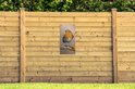 Tuinposter met roodborstje, gemonteerd aan een houten schutting in een tuin.