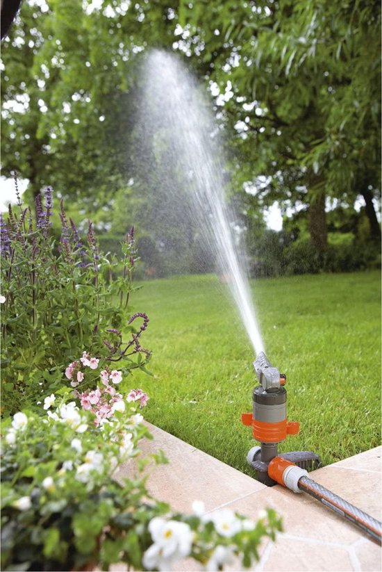 GARDENA turbinesproeier in gebruik, sproeit water op een groen gazon naast bloemen