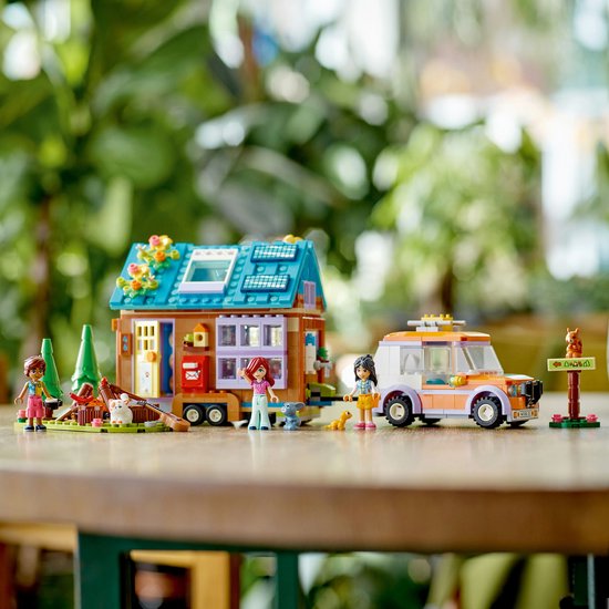 LEGO Friends Tiny House met caravan en auto. De set bevat 3 minipoppen, een hond, een konijn en een eekhoorn. Turquoise dak met zonnepanelen, oranje auto.